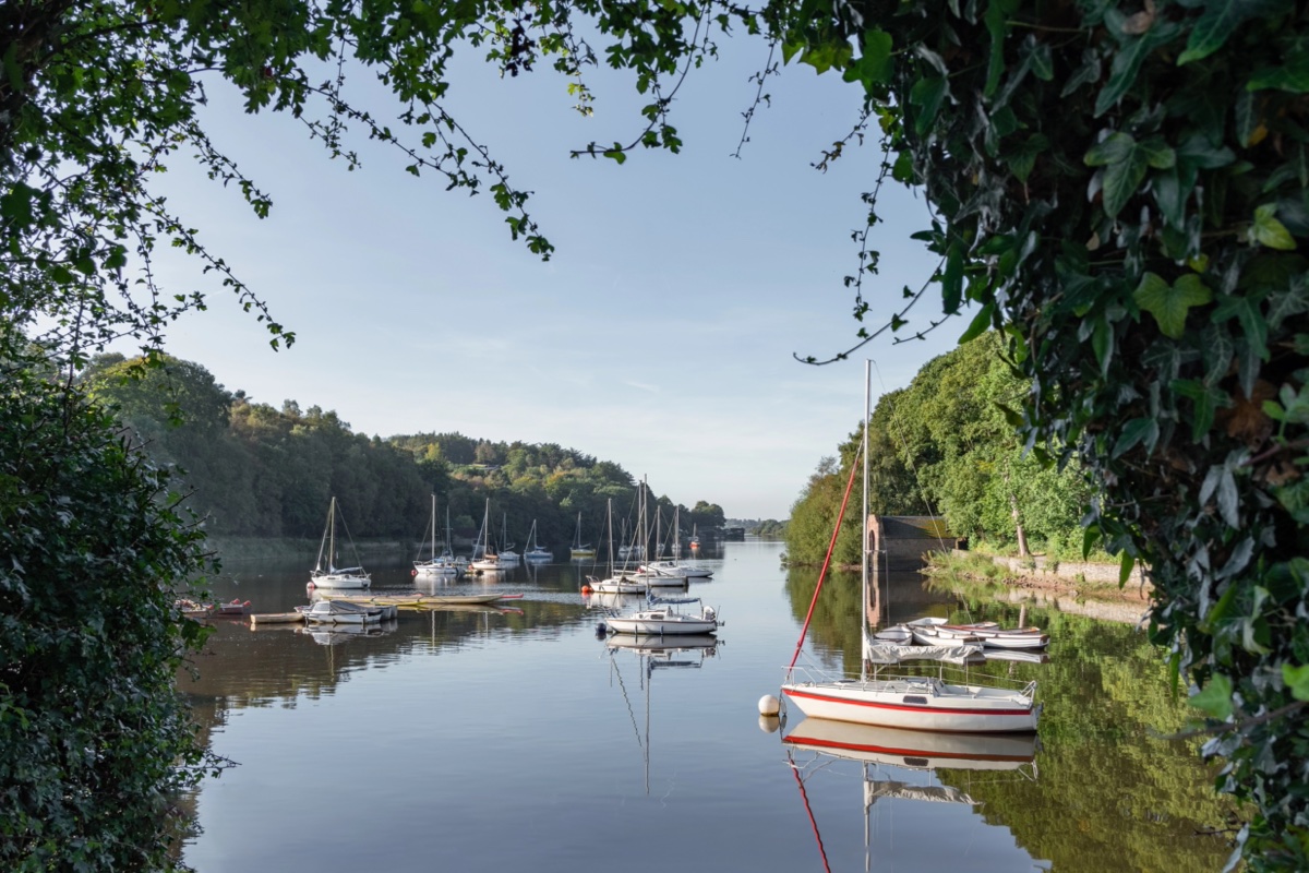 Sailing boats and their reflections framed by trees at Rudyard Lake in Staffordshire
