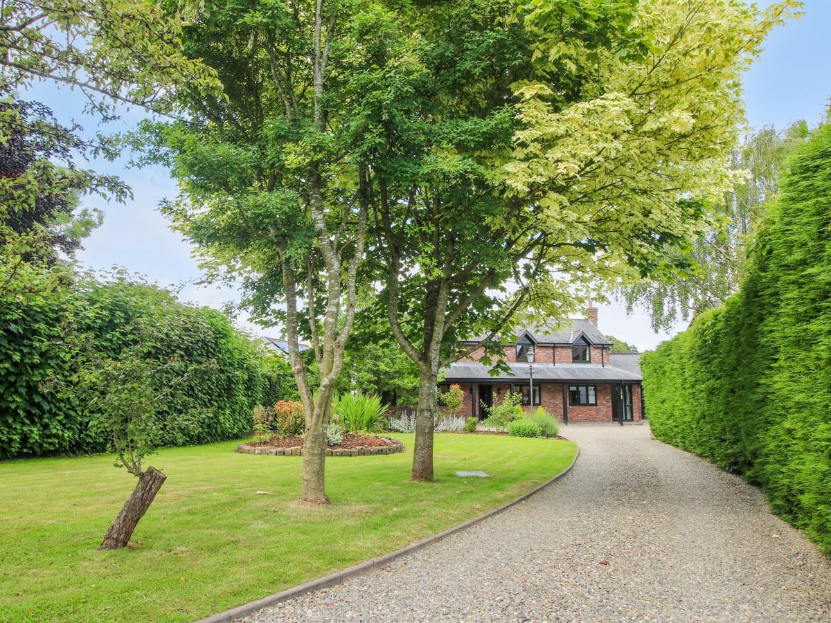 Tree-lined gravel drive and lawn leading to the brick exterior of 1 Clarkes Lane