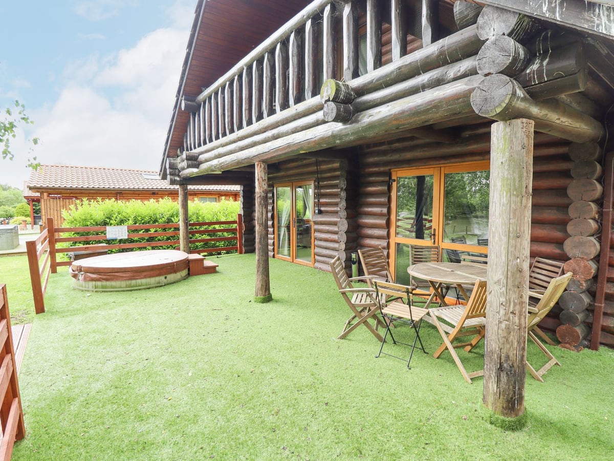 Log exterior of 10 Duck Lagoon with balcony, dining terrace and round hot tub