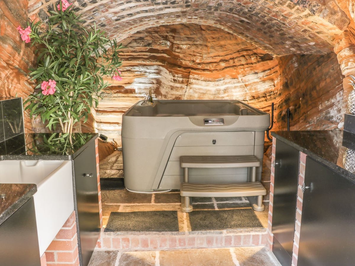 Hot tub beneath the brick arch and sandstone ceiling of the cave room at 31 Riverside