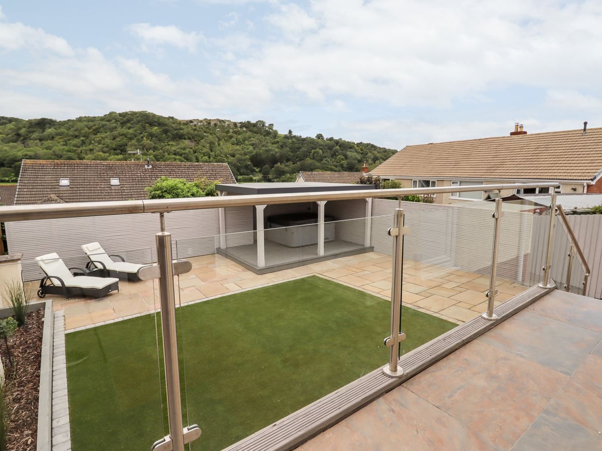 4 Bodnant Road rear garden seen from the raised patio: artificial lawn, loungers and covered hot tub