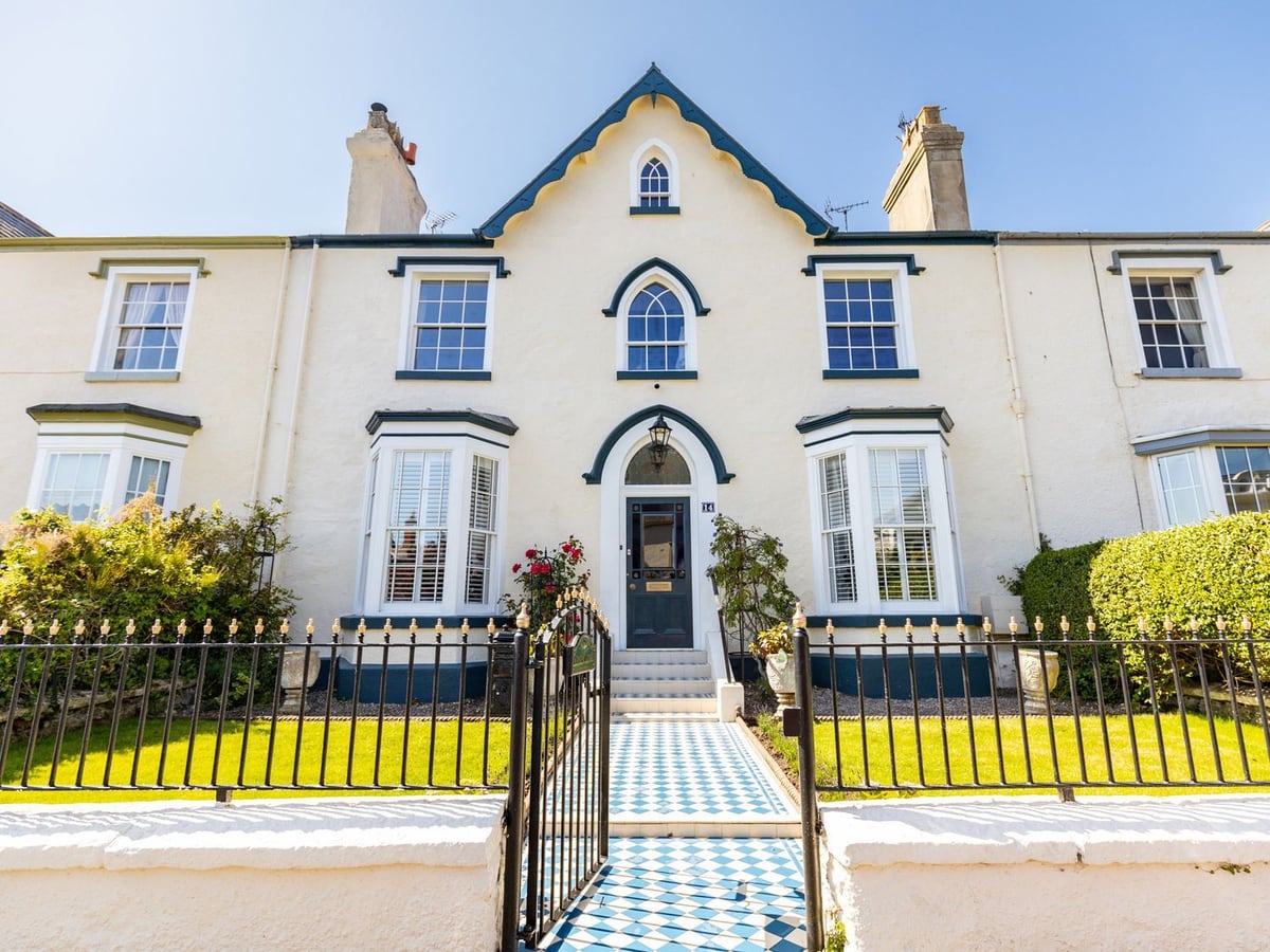 Abbey Lodge white terraced house front with small lawns, iron railings and a gated tiled path
