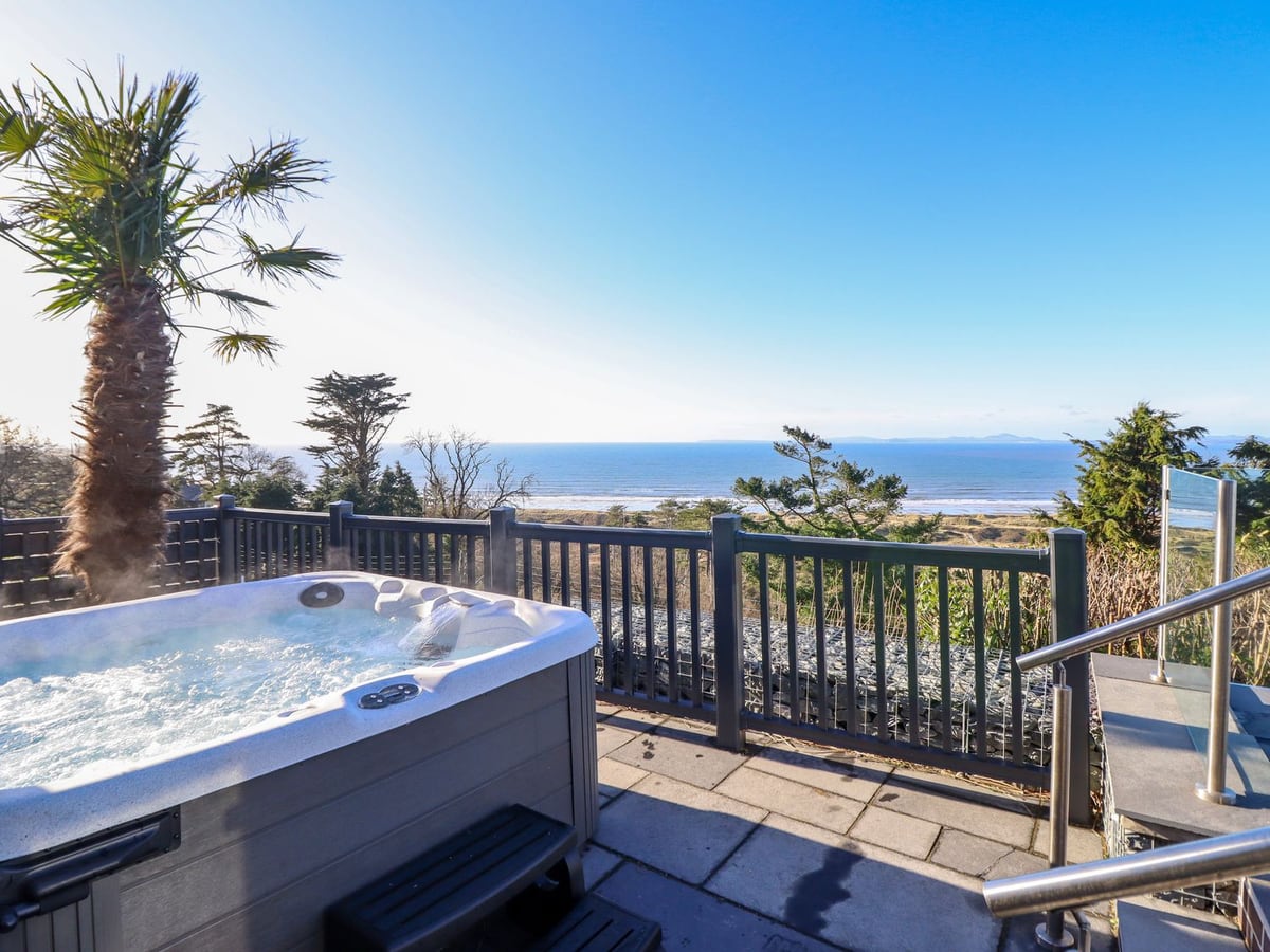 Aelfor hot tub on a terrace with sea views and mountain skyline beyond the rail