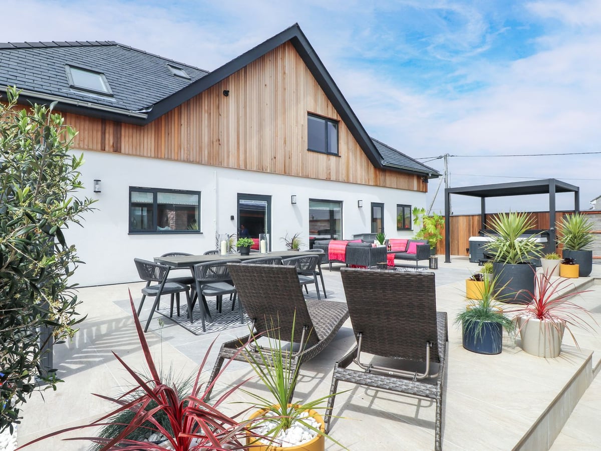 Ardwyn exterior with paved patio, outdoor sofas and dining chairs beside the house