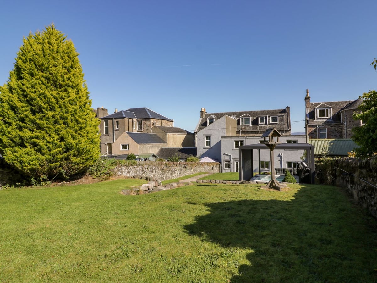 Argyle House rear garden with a lawn, stone steps and covered hot tub below neighbouring houses