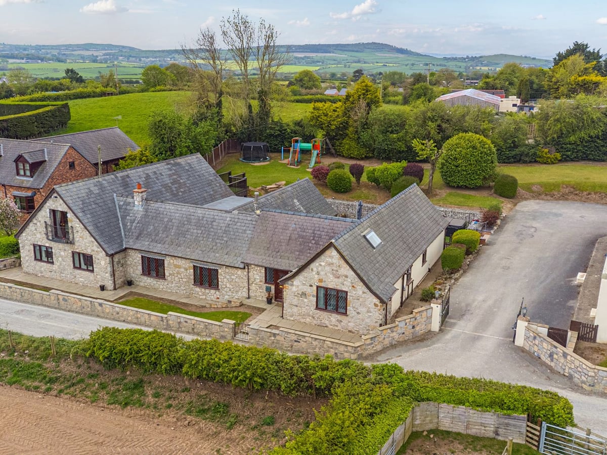 Aerial view of Arosfa, a stone house with rear lawn, play equipment and farmland beyond