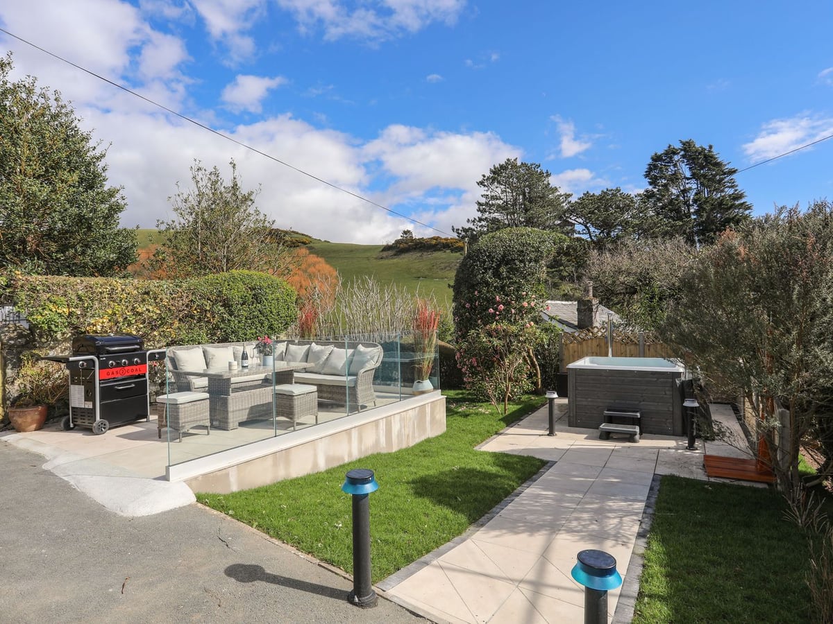 Awelfryn garden terrace with hot tub, outdoor seating, barbecue, and hillside view