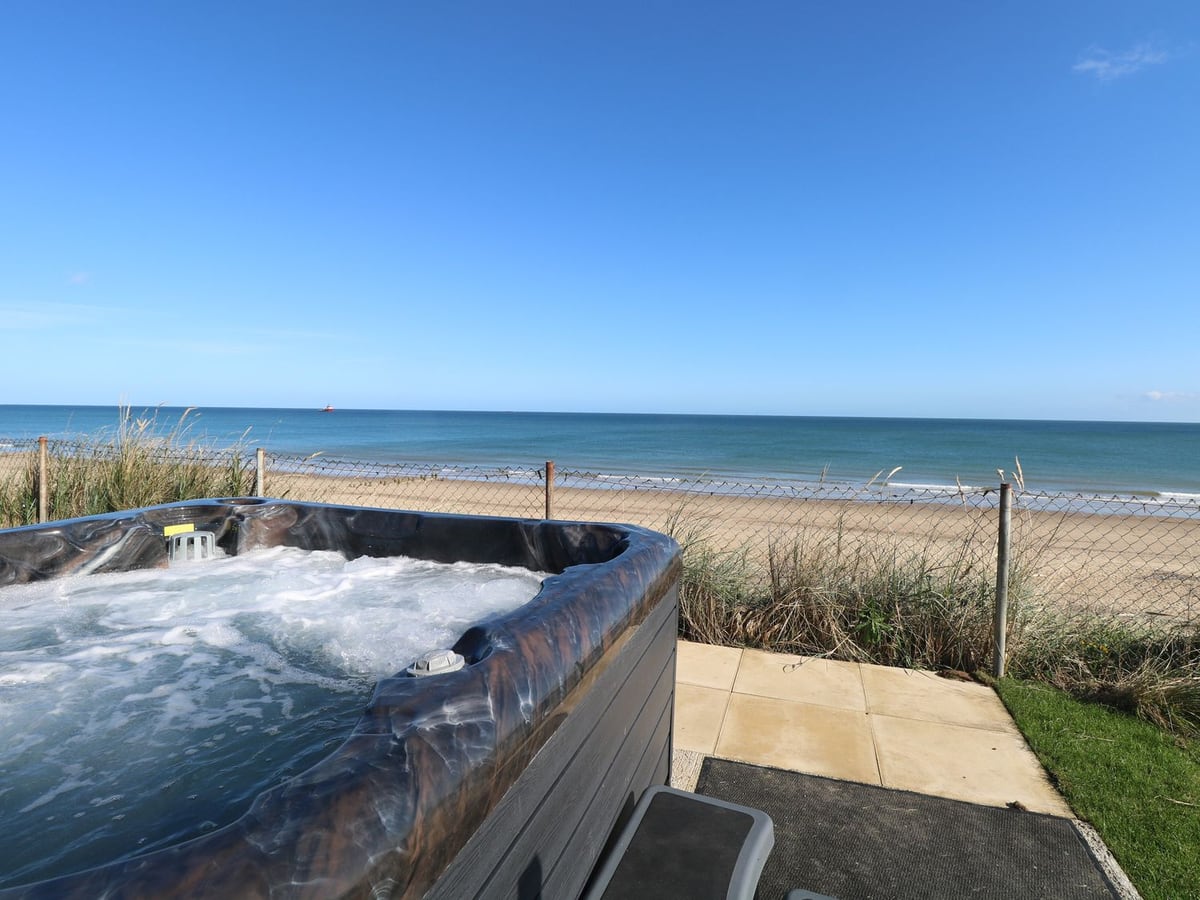 Hot tub on a paved patio overlooking the beach and sea at Beach Haven in Cart Gap