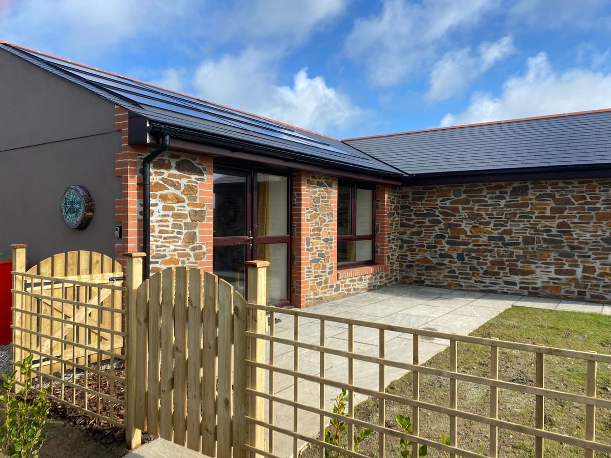 Bimbling Cottage's stone exterior, with a timber gate opening onto a patio and small lawn