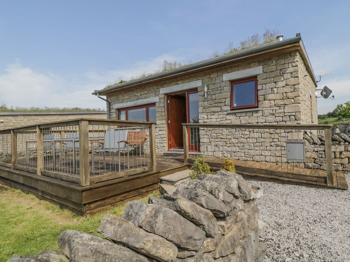 Boavista stone cottage with a grass roof, timber deck and rocks beside the entrance
