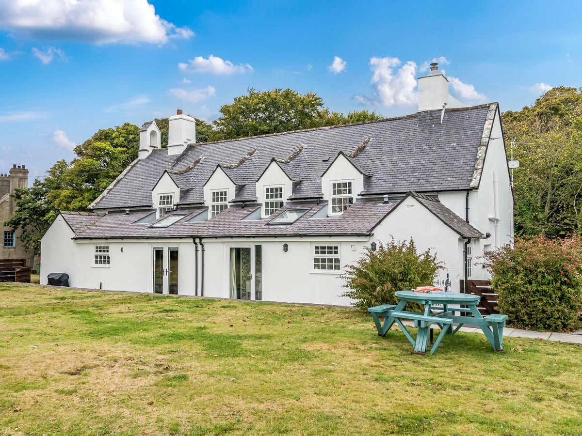 Bodior Garden Cottage with its rear lawn, picnic table and white-painted exterior