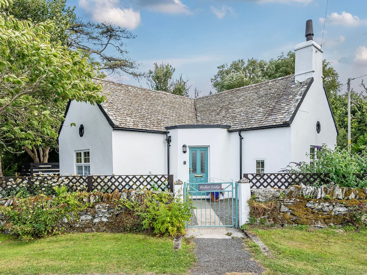 Bodior Lodge white-painted exterior with a green front gate, gravel path and planting