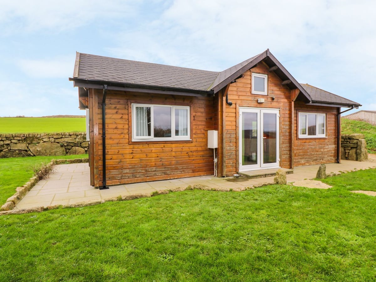 Borah Lodge's timber exterior beside a lawn and stone boundary wall, with green fields beyond