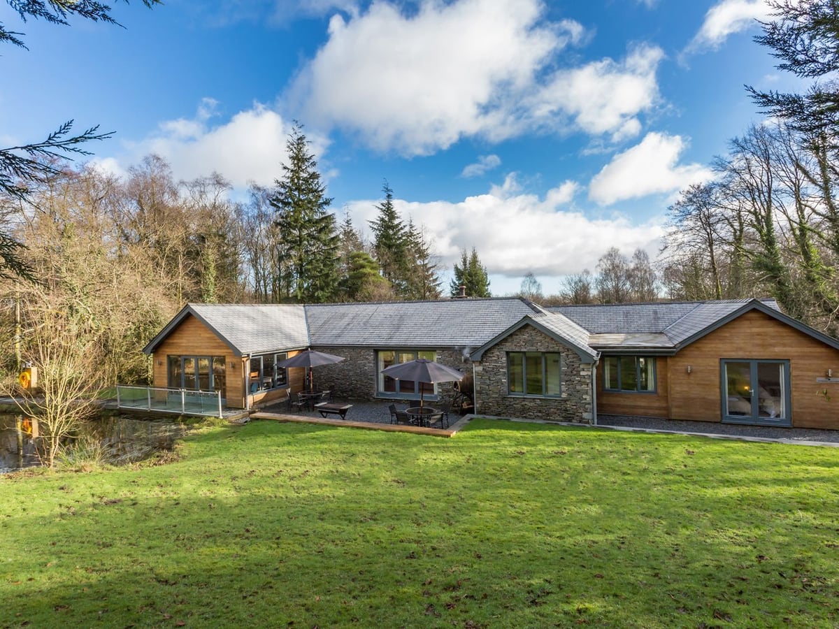 Bracken Ground stone and timber exterior with a broad lawn, terrace and trees behind