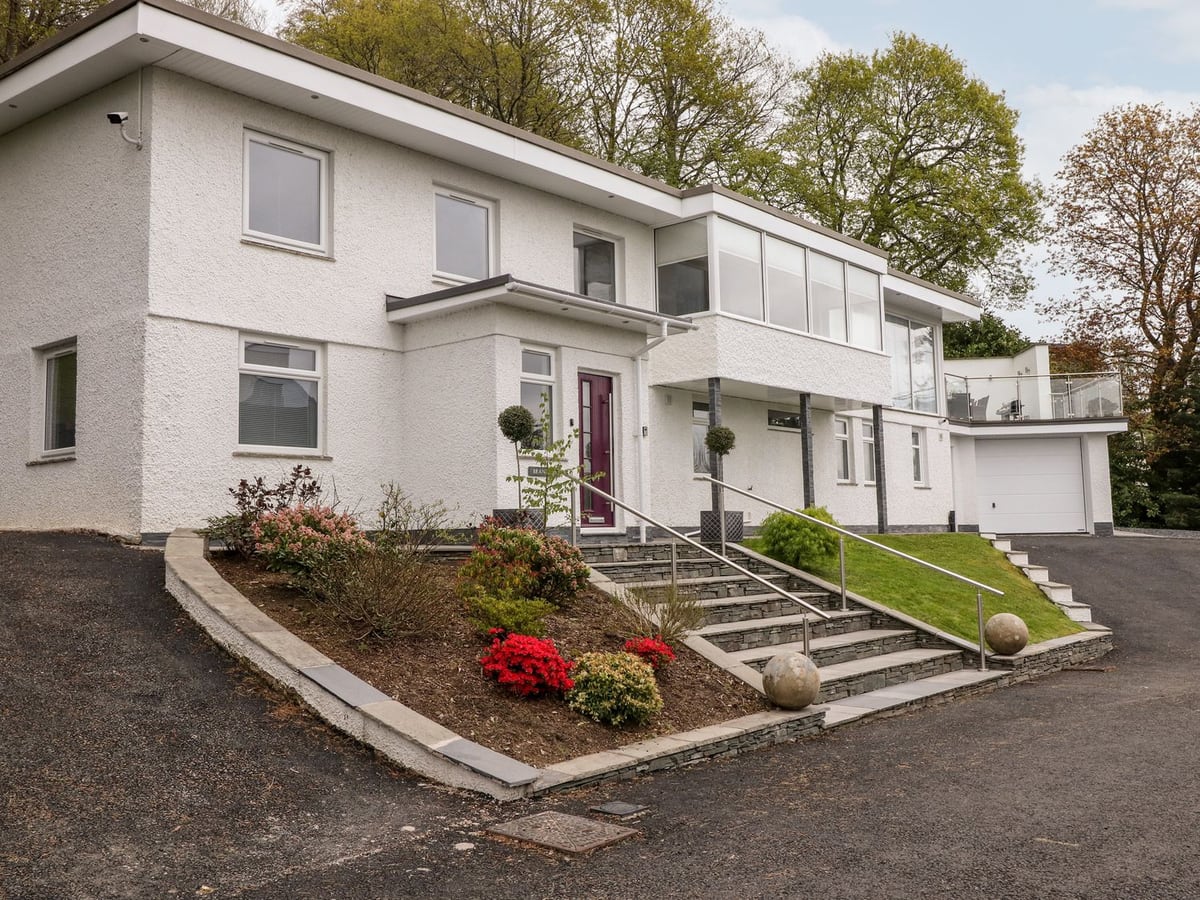 Brantlea white exterior with broad stone steps, planted borders and a glass-sided terrace