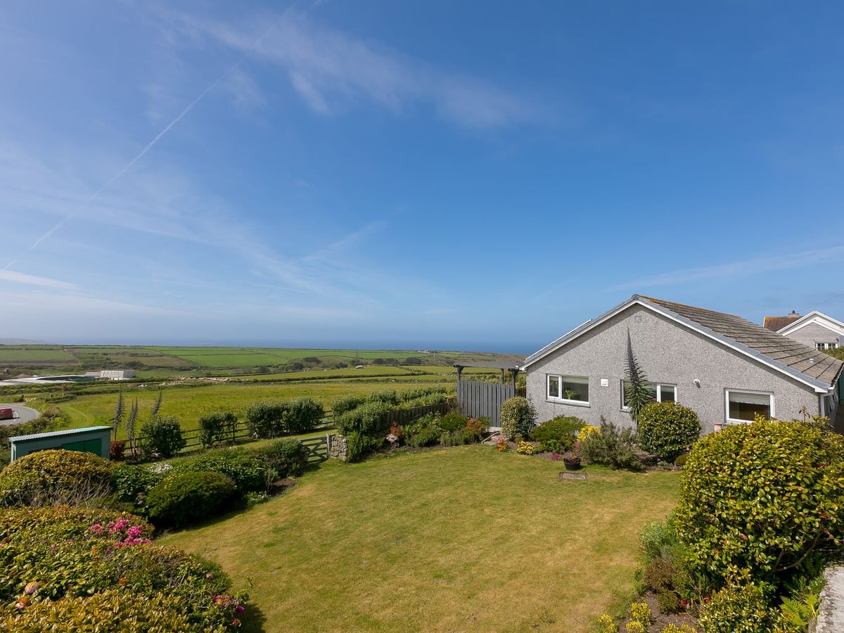 Broadlands bungalow beside a broad lawn and flowering borders, with fields and sea beyond