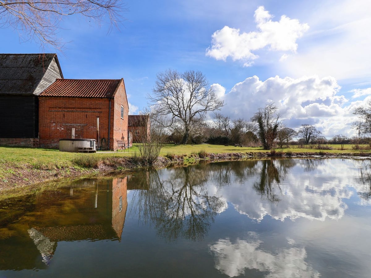 Brook Farm reflected in the pond with its brick exterior