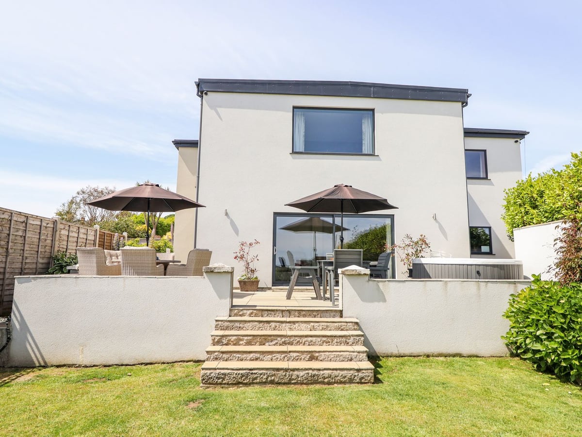Bryn Mor rear exterior with patio seating, a covered hot tub and steps down to the lawn