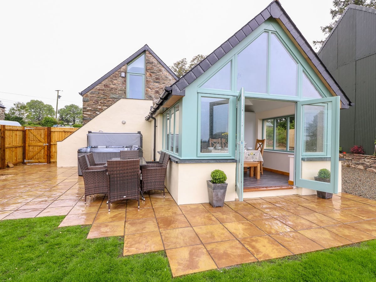 Bwthyn Eisteddfa Fach with glazed doors, patio dining and a hot tub beside the lawn