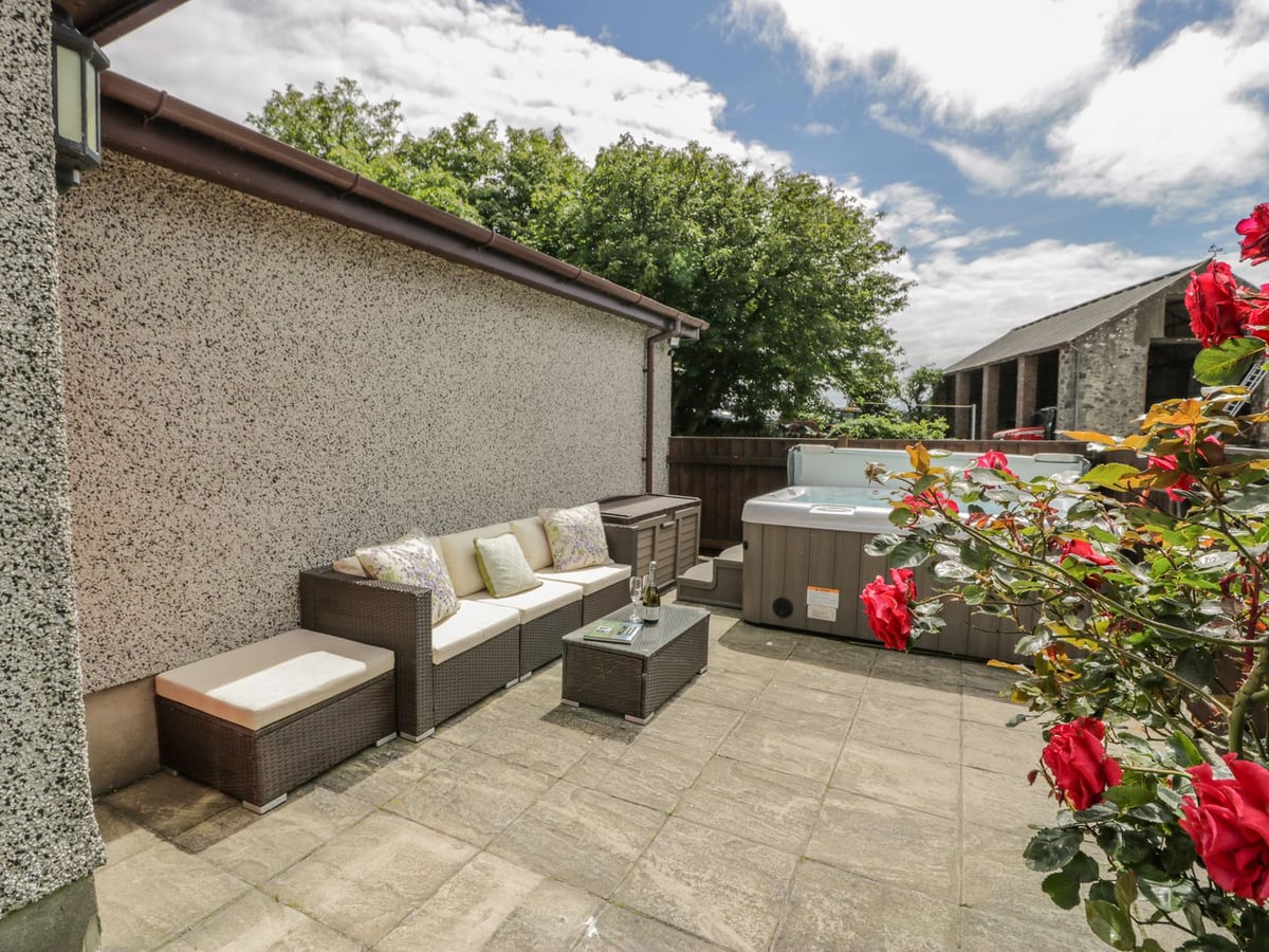 Bwthyn Pengwern enclosed courtyard with outdoor seating, flowers, and hot tub