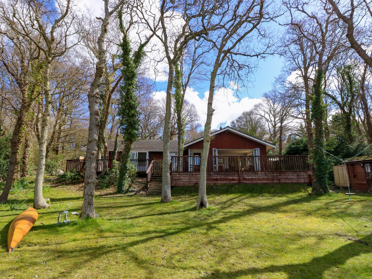 Byewater timber lodge with lawn, deck and trees beside the water in Wootton