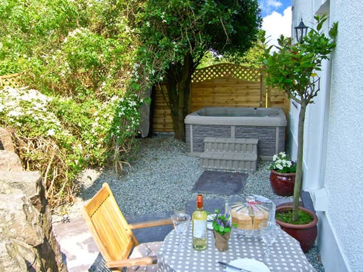 Carreg Rhys gravel courtyard with a hot tub, garden table and chairs beside the cottage