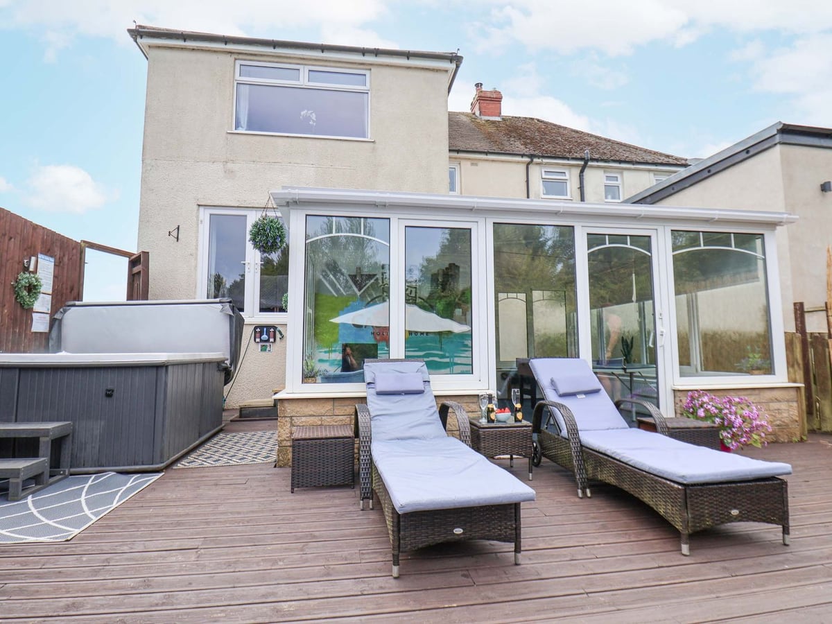 Rear patio with hot tub, loungers and house exterior at Castle View near Scarborough