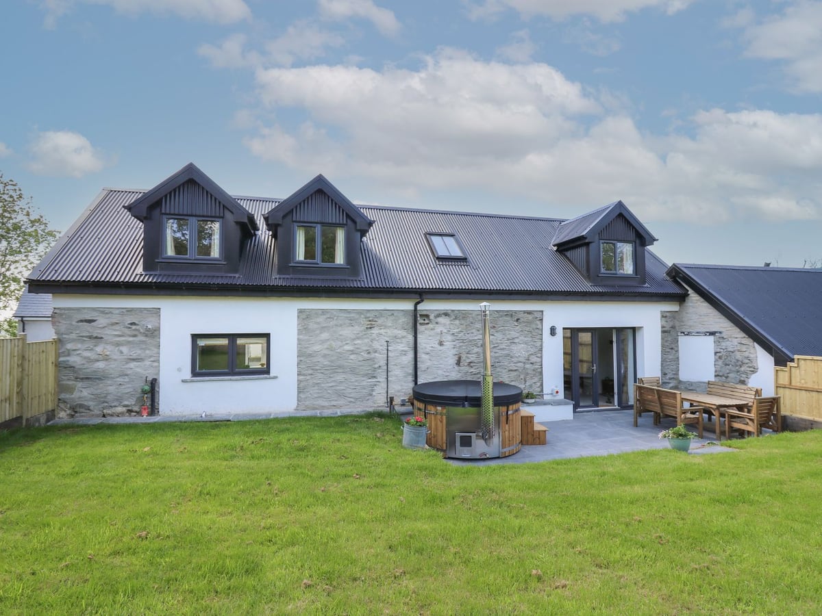 Cattle Tree Cottage rear with wood-fired hot tub, slate patio, outdoor table and lawn