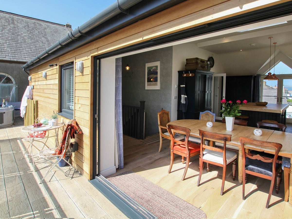 Chapel House dining room opening onto a raised terrace with outdoor chairs and hot tub
