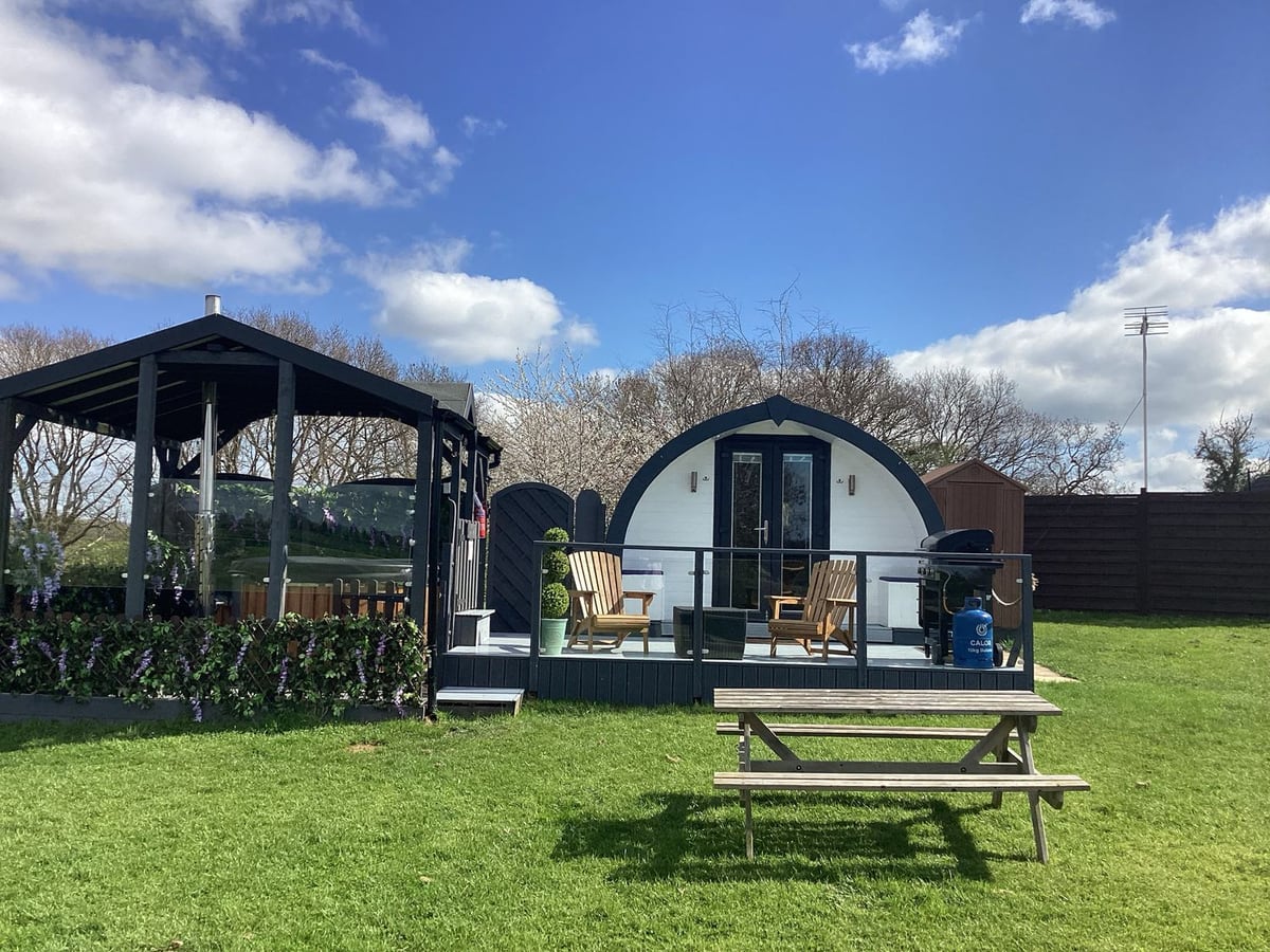 Cherry Pod with a covered hot tub, raised deck, picnic table and lawn in front