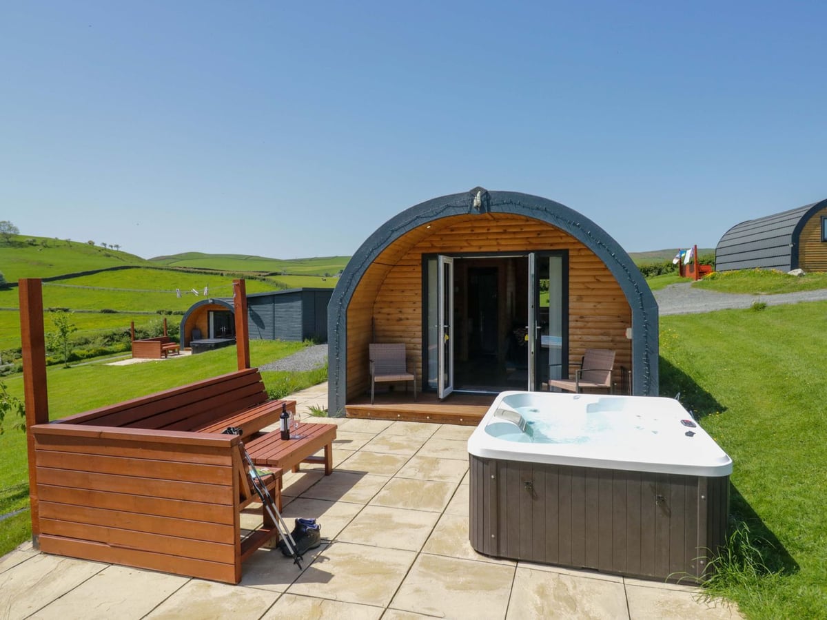 Cherry timber pod beside its hot tub and red wooden bench on a paved terrace
