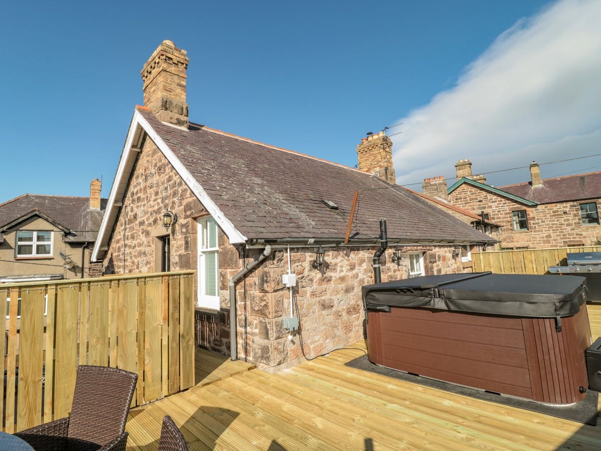 Covered hot tub and timber decking beside the stone gable of Cheviot Hills in Wooler.