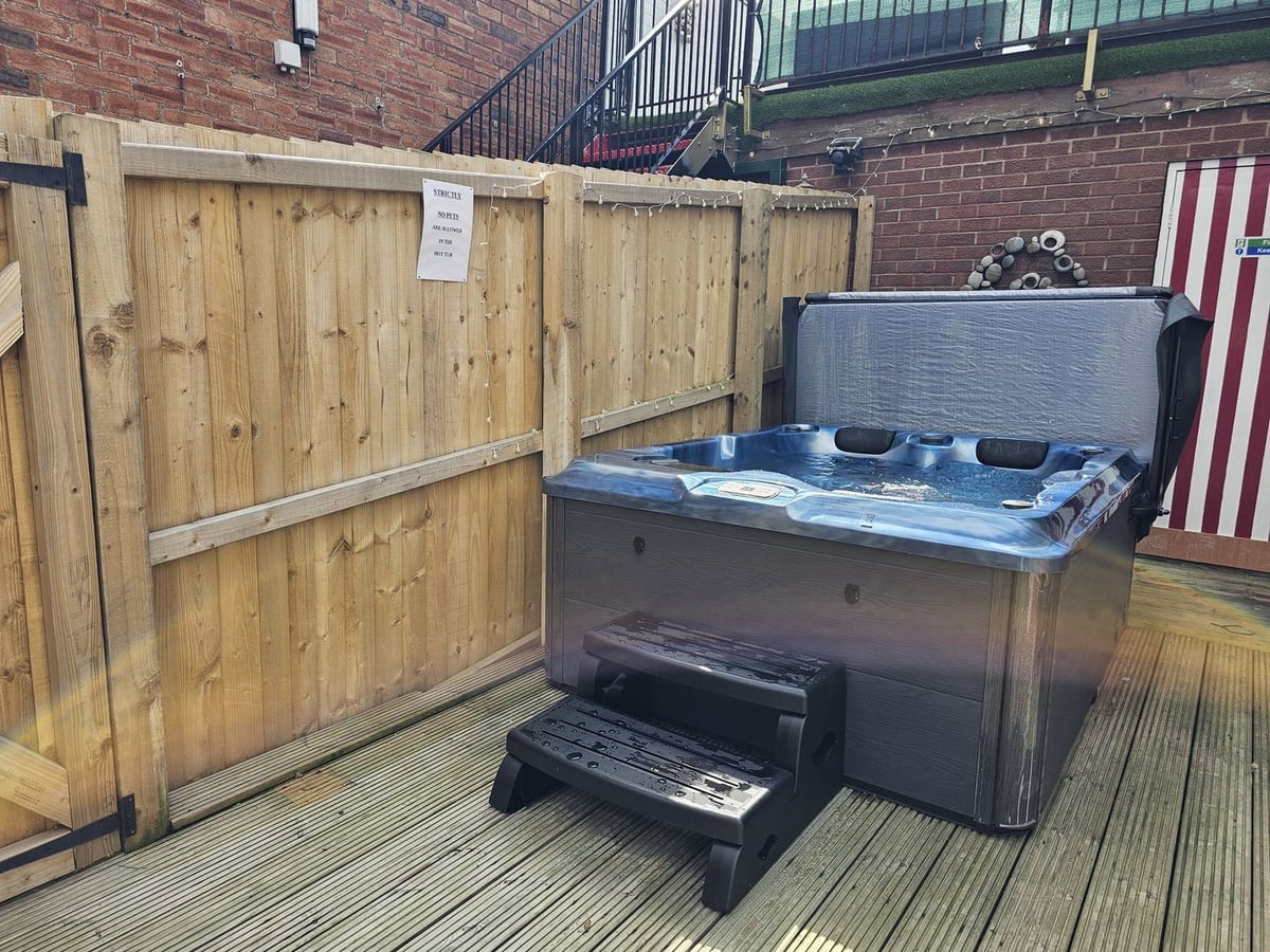 Hot tub on Circus Circus's timber deck with tall wooden fencing and the striped studio door