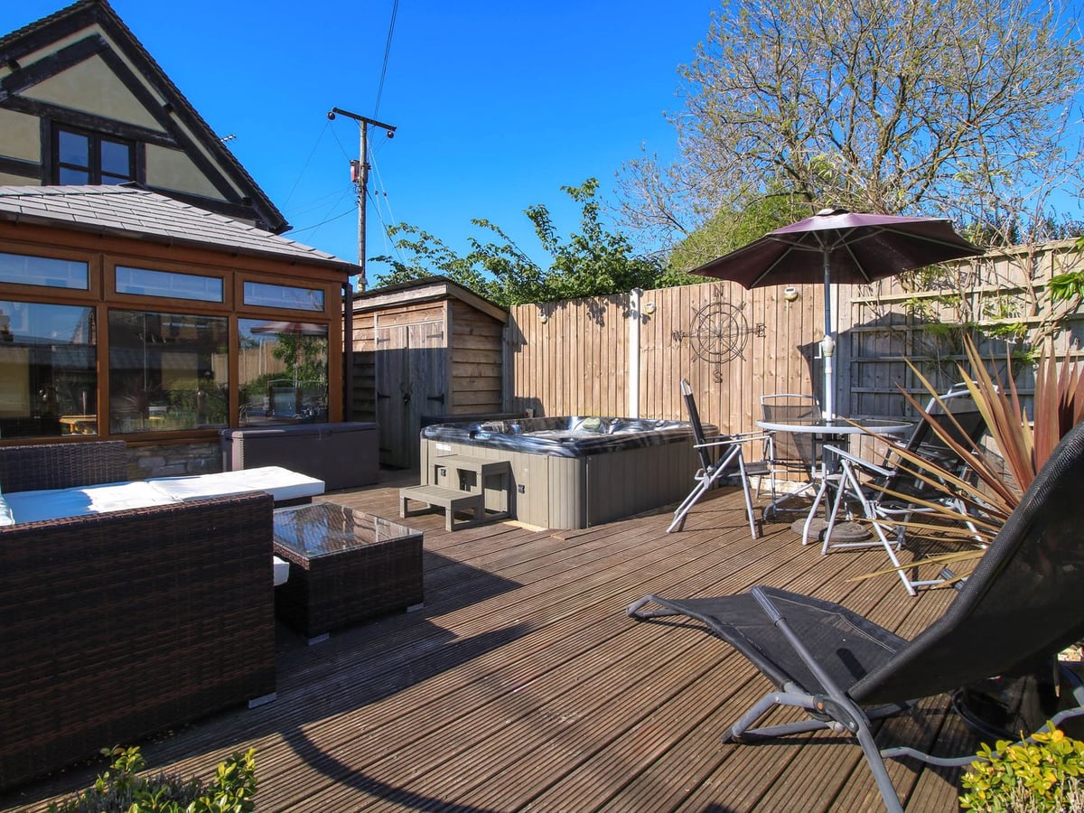 Hot tub and outdoor seats on the wooden deck beside Clandyke Cottage's conservatory