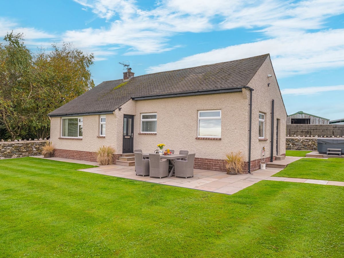 Colt Park Cottage with a lawn, patio table and hot tub beside its single-storey exterior