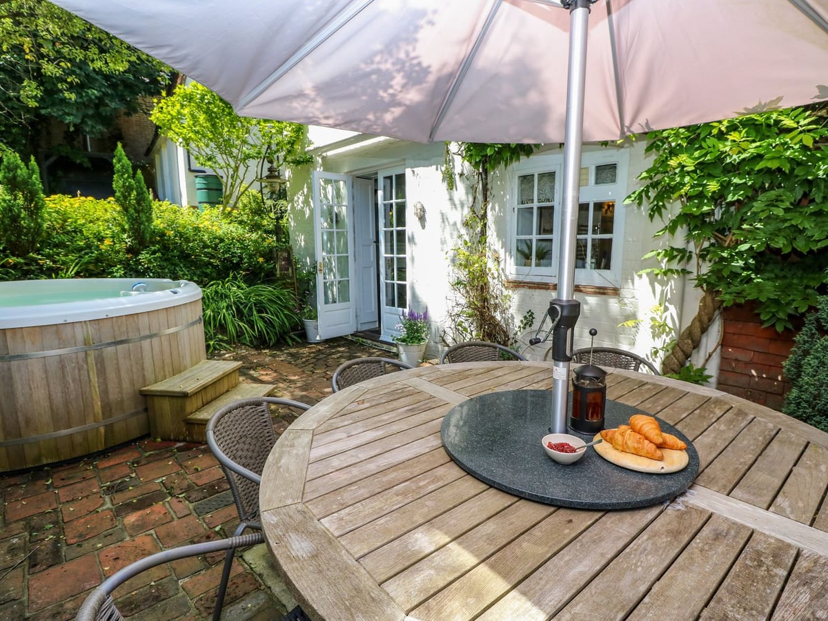 Coppice Hill House brick patio with hot tub and outdoor dining by the cottage