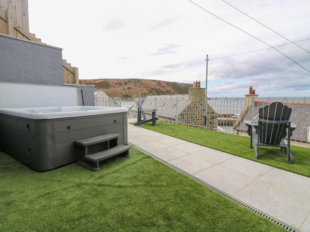 Hot tub and outdoor chairs on a raised terrace at Craignure, with village roofs and sea beyond