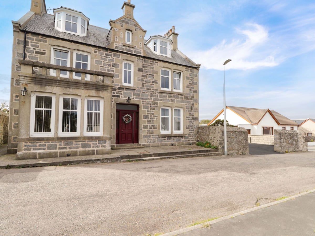 Crannoch Self Catering stone house beside the street, with bay windows and a red front door