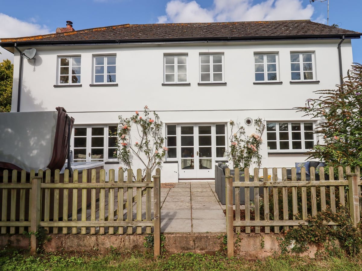White cottage facade and glazed doors behind the picket patio fence at Culver Court Cottage