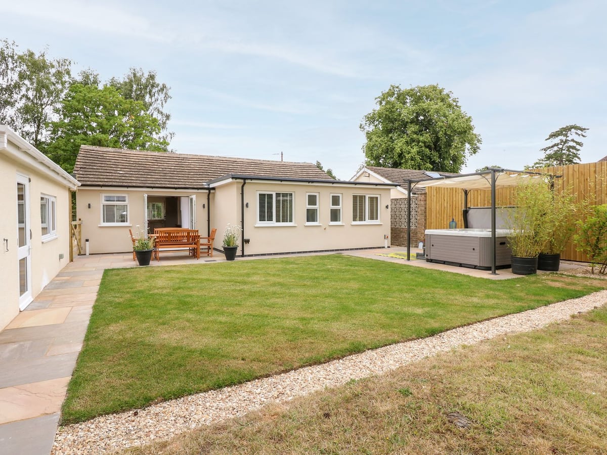 Daisy Tree Cottage's lawn beside the bungalow, dining patio and sheltered hot tub