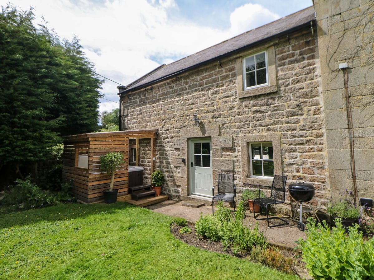 Dale End Farm Cottage with stone walls, a lawn, patio chairs and timber hot-tub shelter