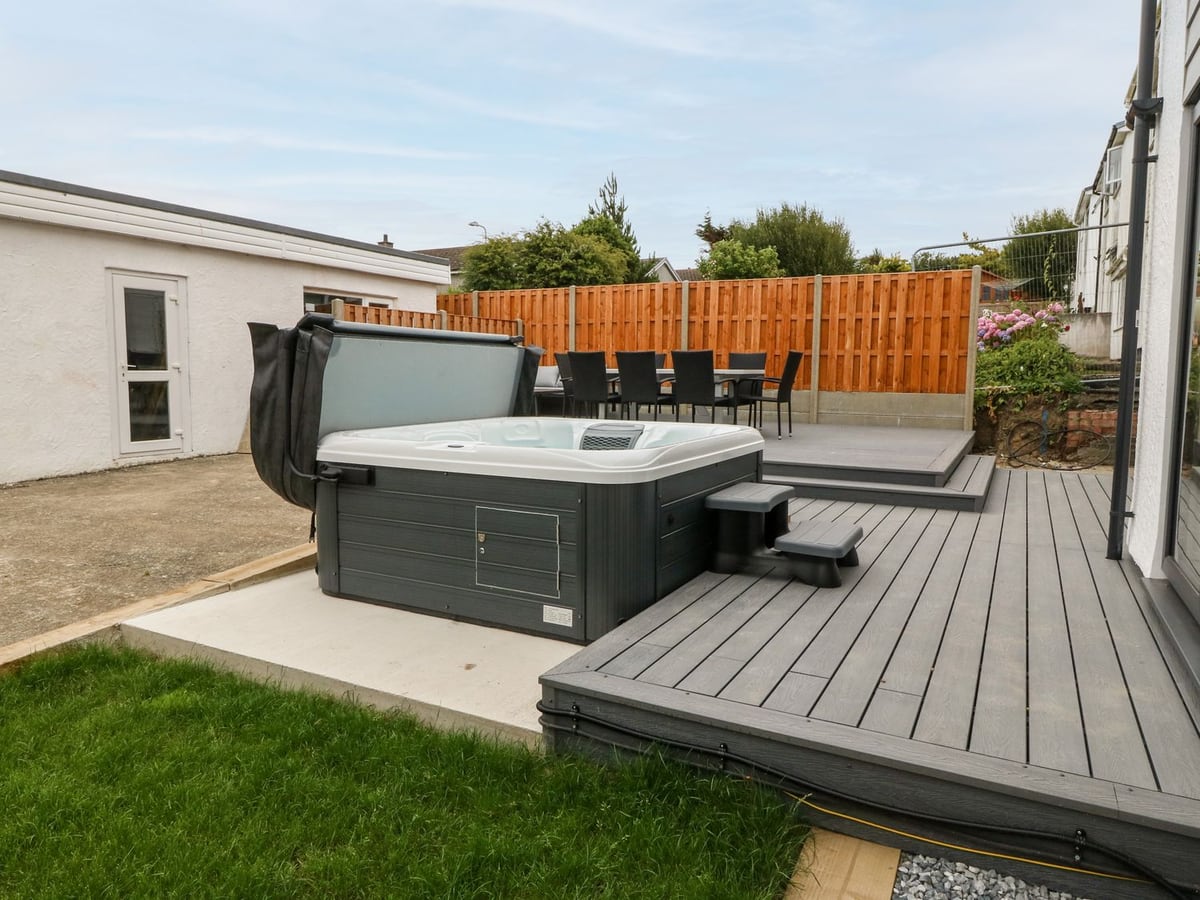 Daresfield rear garden with lawn edge, stepped decking, an outdoor table and a hot tub
