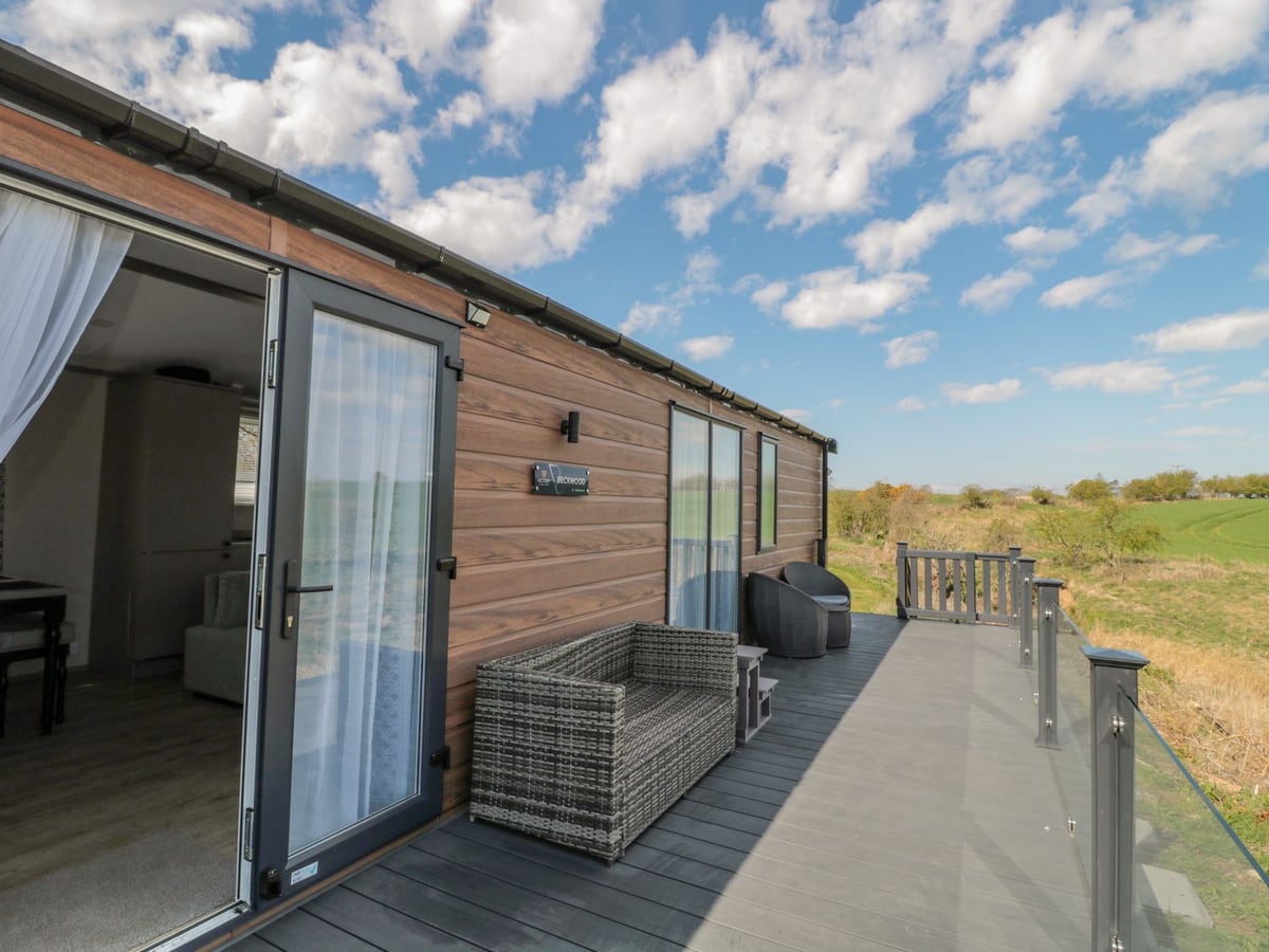 Decking and outdoor seating beside Dreams & Streams, with open fields beyond the railing.