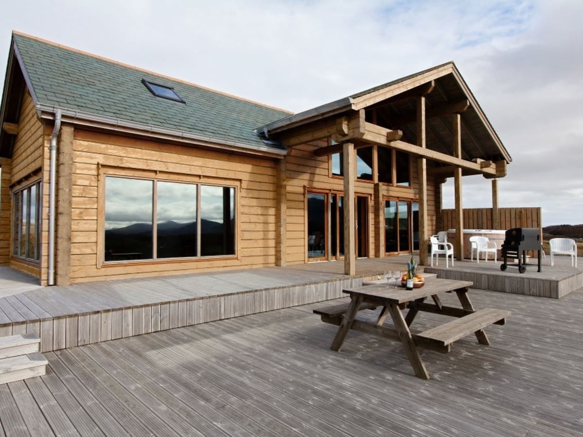 Eagle Lodge timber exterior with a broad deck, picnic table and sheltered outdoor seats