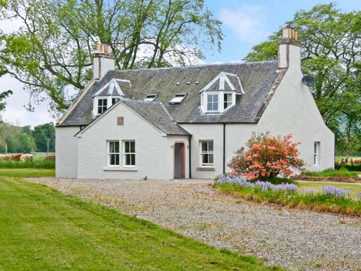 Easter Urray Farmhouse with white walls, a gravel drive, lawn and flowering shrubs