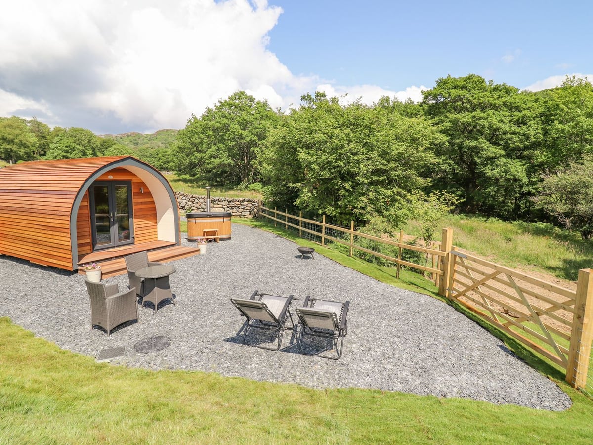Eirlys timber pod with hot tub, gravel seating area, two loungers and a wooden field gate