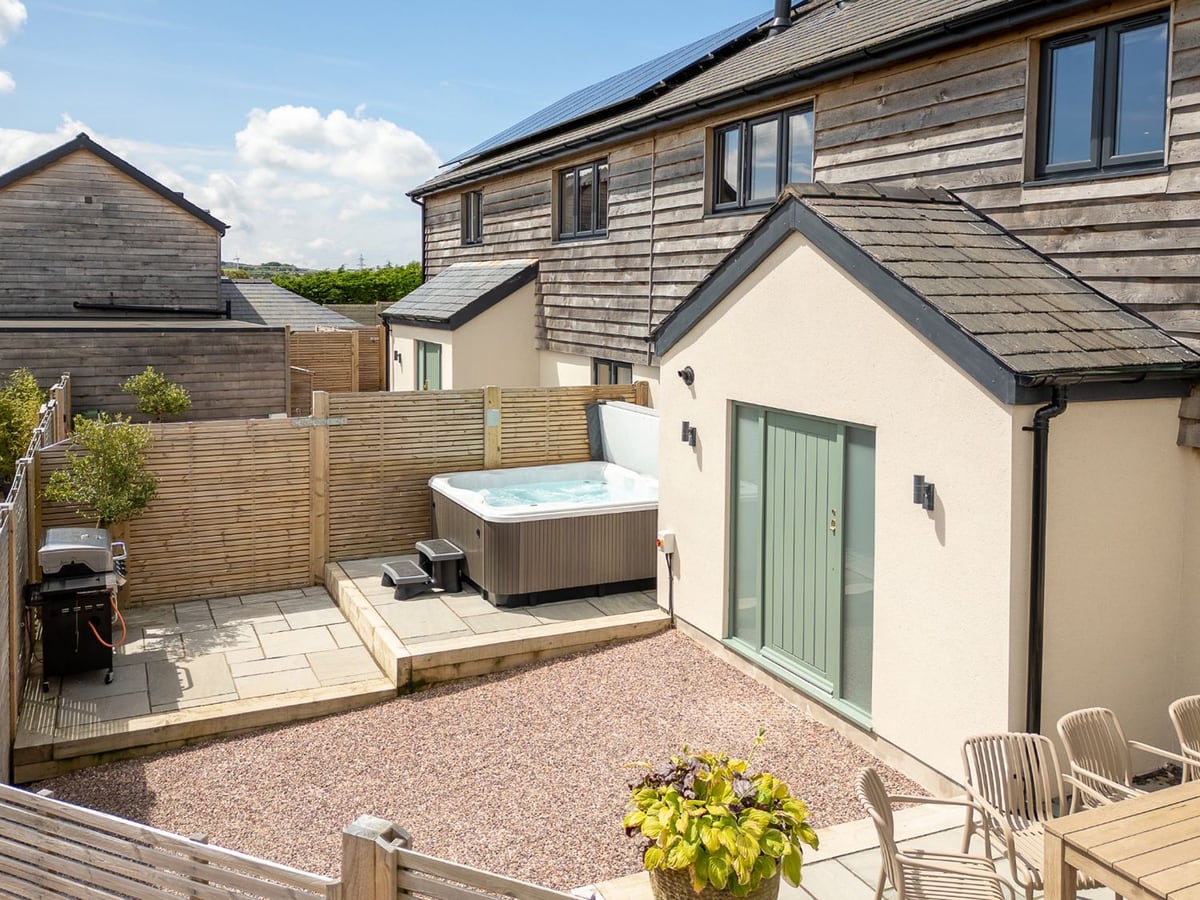 Farmyard House patio with open hot tub, fenced gravel yard, BBQ and outdoor dining chairs
