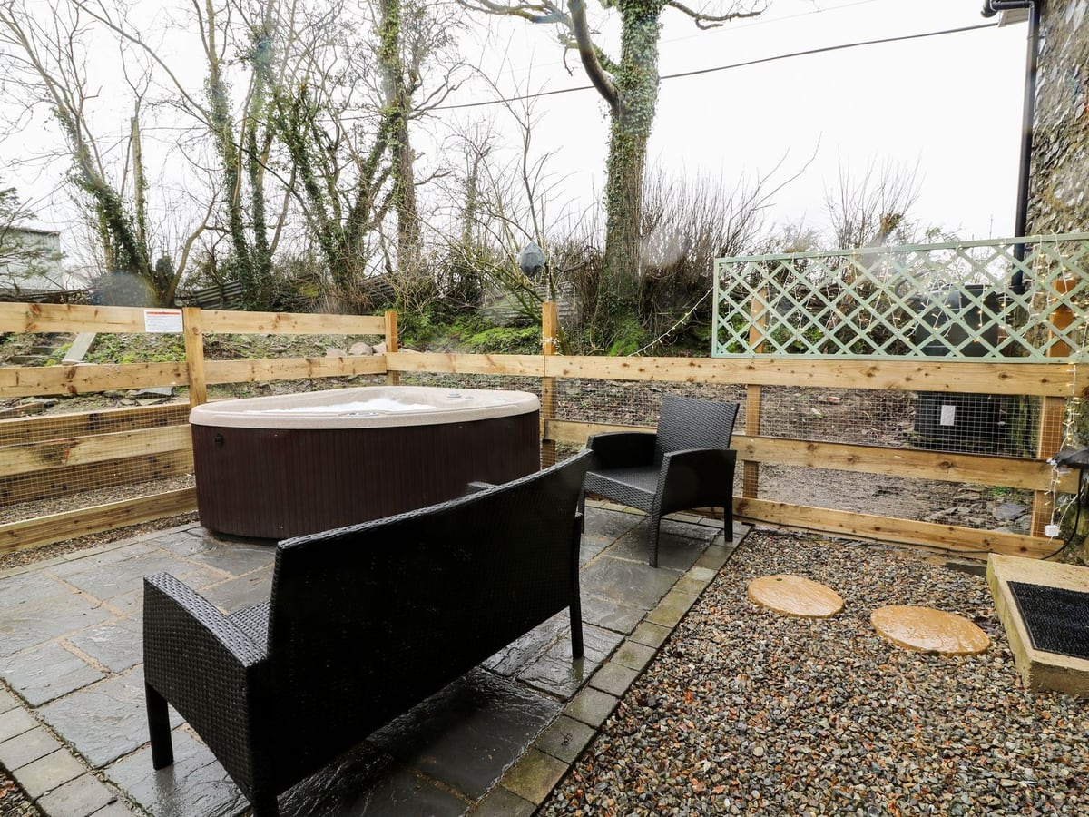 Field View gravel and paved patio with hot tub and wicker seating by a timber and mesh fence