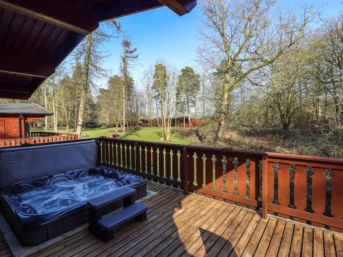 Hot tub on Forest Lodge's timber veranda overlooking trees at Kenwick Park
