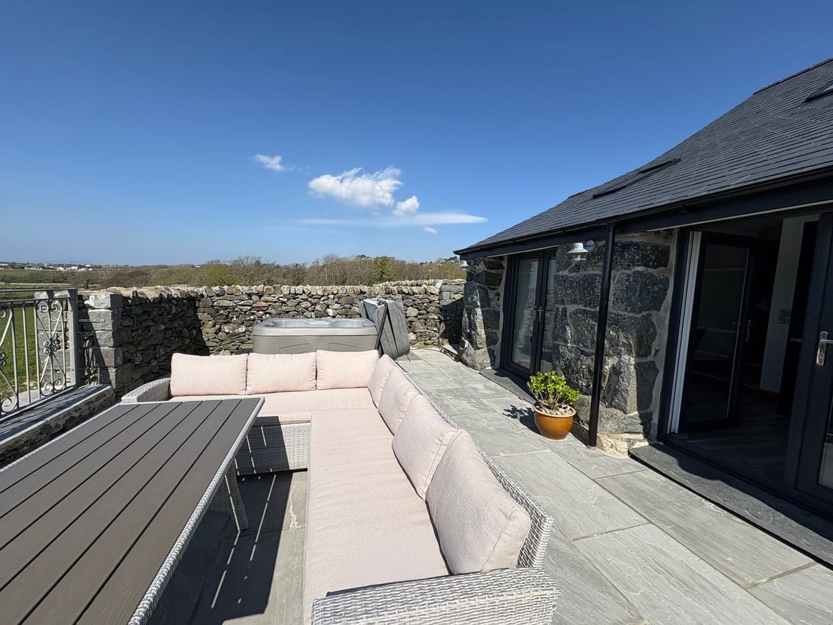 Gaerau Bach stone exterior with patio seating, hot tub, and low stone wall